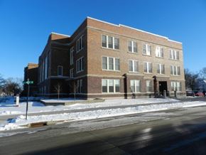 Spencer apartment for rent - A large brick building with a snow-covered ground in front.