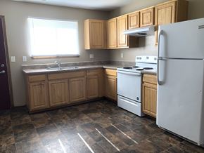 Cedar Rapids apartment for rent - A kitchen with a white refrigerator, white stove, and wooden cabinets.