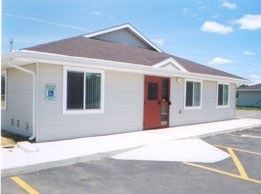 Council Bluffs apartment for rent - A small building with a red door and a parking lot in front.