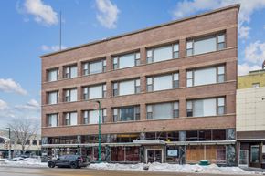 Clinton apartment for rent - A large brown building with many windows sits on a street corner.