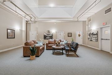 Clinton apartment for rent - A living room with a brown couch, a chair, and a table with a vase of flowers on it.