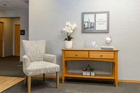 Adel apartment for rent - A chair and a table with a vase of flowers on it.