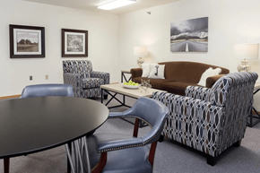 Adel apartment for rent - A living room with a brown couch, a round table, and two chairs.