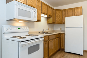 Adel apartment for rent - A white stove and microwave in a kitchen with wooden cabinets.