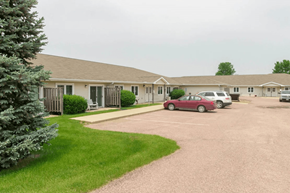 Moville apartment for rent - A parking lot in front of a building with a red car parked.
