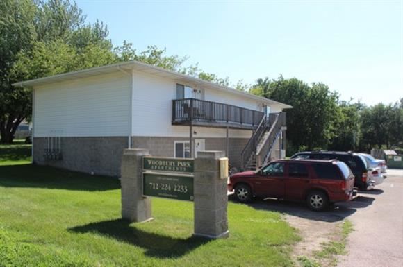 Sioux City apartment for rent - A sign for Woods at Park is in front of a building and a red vehicle.