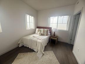 Hawarden apartment for rent - A bedroom with a bed, a small table, and a rug.