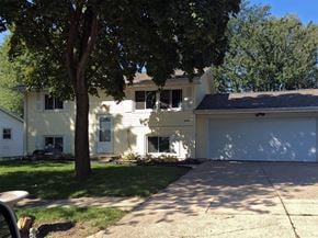 Cedar Rapids apartment for rent - A house with a white garage door and a tree in front.