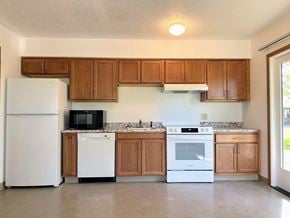 Adel apartment for rent - an empty kitchen with white appliances and wooden cabinets