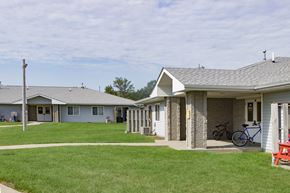 Hawarden apartment for rent - A grassy area in front of a building with a bicycle leaning against the wall.