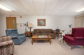 Lake Park apartment for rent - A living room with a blue chair, a red chair, a wooden coffee table, and a lamp.