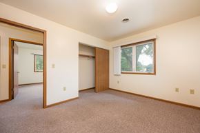 Spirit Lake apartment for rent - A room with a carpeted floor and a window showing trees outside.