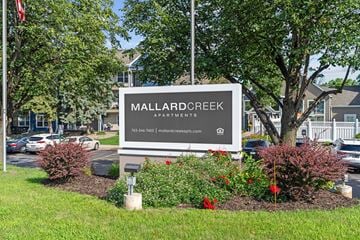 Golden Valley apartment for rent - A sign for Mallard Creek Apartments is surrounded by flowers and greenery.
