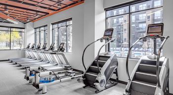 A gym with cardio equipment and a row of exercise machines