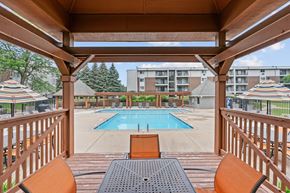 Burnsville apartment for rent - A wooden deck with a table and chairs overlooking a pool.