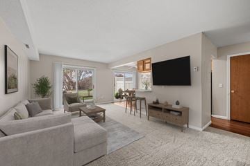 Robbinsdale triplex for rent - A living room with a grey couch and a flat screen TV mounted on the wall.