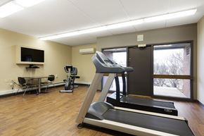 Robbinsdale apartment for rent - A treadmill is in the middle of a room with a television and exercise equipment.