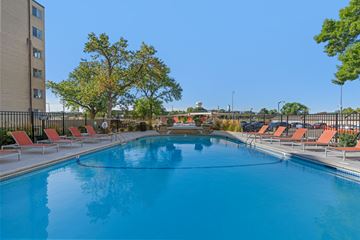 St. Louis Park apartment for rent - A large outdoor swimming pool surrounded by red lounge chairs.