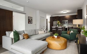 St. Louis Park apartment for rent - A modern living room with a grey sofa and a yellow ottoman.