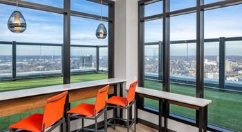 A dining area with orange chairs and a view of the city