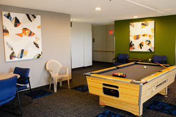 St. Paul apartment for rent - A pool table is in the middle of a room with chairs and artwork on the walls.