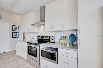 Designer kitchen with stainless vent hood, herringbone backsplash and quartz counters