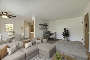 Fridley apartment for rent - A living room with a grey couch, a coffee table, and a ceiling fan.