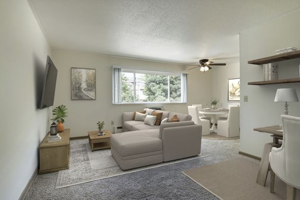 Fridley apartment for rent - A living room with a grey couch, a white chair, and a television on the wall.