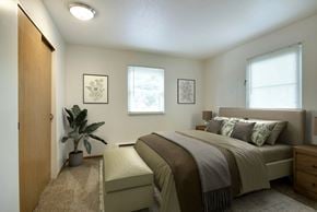 Fridley apartment for rent - A bedroom with a bed, nightstand, and a plant.