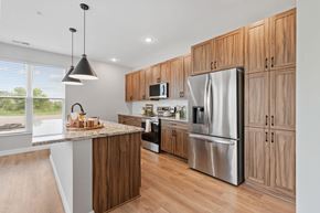 Rogers townhouse for rent - A modern kitchen with wooden cabinets and a marble island. at Townhomes at Preserve, Rogers, Minnesota