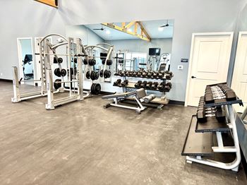 A gym with a variety of equipment including weights and benches.