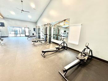A gym with a variety of equipment including treadmills, weights, and a fan.