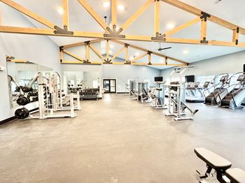 A gym with a variety of equipment and a large mirror on the wall.