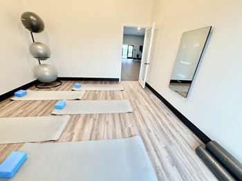 A yoga studio with a mirror and yoga mats on the floor.