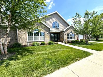 The front of a house with a lawn and trees