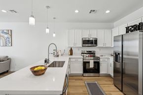 Las Vegas townhouse for rent - A modern kitchen with white cabinets and stainless steel appliances.