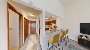 West Allis apartment for rent - A hallway with a striped carpet leads to a kitchen area with a bar and chairs.