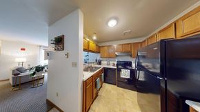 Pewaukee apartment for rent - A kitchen with a black refrigerator and wooden cabinets.