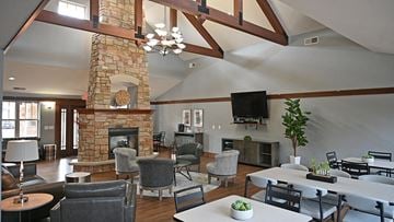 Greenfield apartment for rent - a large living room with a stone fireplace and tables and chairs