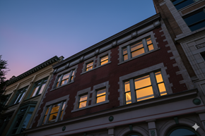 Buffalo apartment for rent - A row of buildings with windows lit up at dusk.