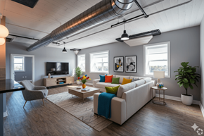 Buffalo apartment for rent - A living room with a white couch, a chair, a television, and a potted plant.