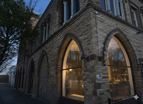 Buffalo apartment for rent - A building with large arched windows and a tree in front.