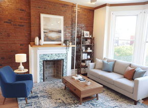 Buffalo apartment for rent - A living room with a blue chair, a white couch, and a fireplace.