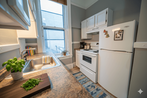 Buffalo apartment for rent - A kitchen with a white refrigerator and a wooden cutting board with green herbs on it.