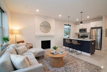 Buffalo apartment for rent - A modern living room with a fireplace and a kitchen area in the background.