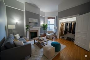 Buffalo apartment for rent - A living room with a grey couch, a coffee table, a fireplace, and a wardrobe.