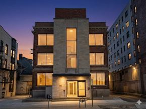 Buffalo apartment for rent - A building with a brick facade stands in the middle of a street at dusk.