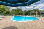 Woodridge apartment for rent - A swimming pool surrounded by a brick patio and lounge chairs under a blue canopy.