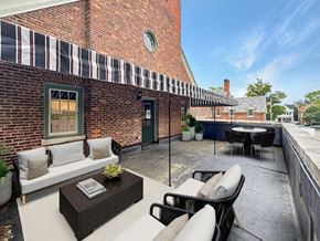 Buffalo apartment for rent - A patio with a table and chairs is set up outside a brick building.