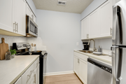 Tampa apartment for rent - A kitchen with white cabinets and stainless steel appliances.at Fernwood Grove Apartments, Tampa, FL